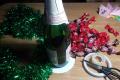 Pudele šampanieša un konfektes, lai izveidotu Ziemassvētku eglīti